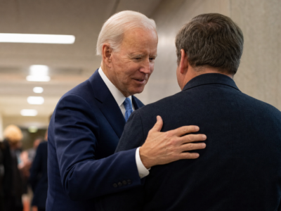 Joe Biden patting a man on the back in a civic hallway