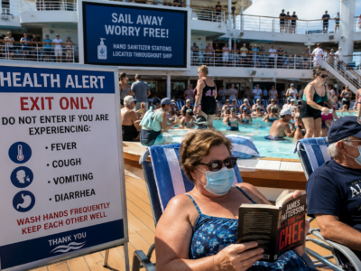 Cruise ship pool deck with a health alert sign and masked passengers beside a crowded pool