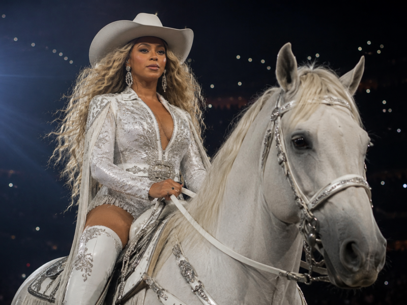 Beyonce in a white cowboy outfit riding onstage during a stadium performance