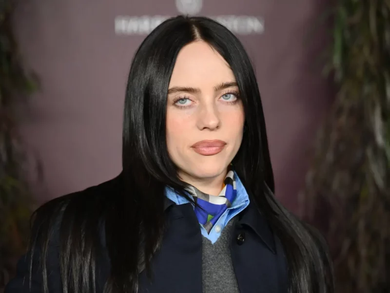 Billie Eilish looking at the camera with pale blue eyes and long black hair at an event.