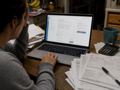 Kitchen table with blurred tax software, W-2 forms, calculator, and mail