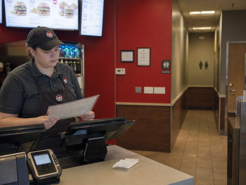 Fast-food counter with receipt and restroom hallway in background